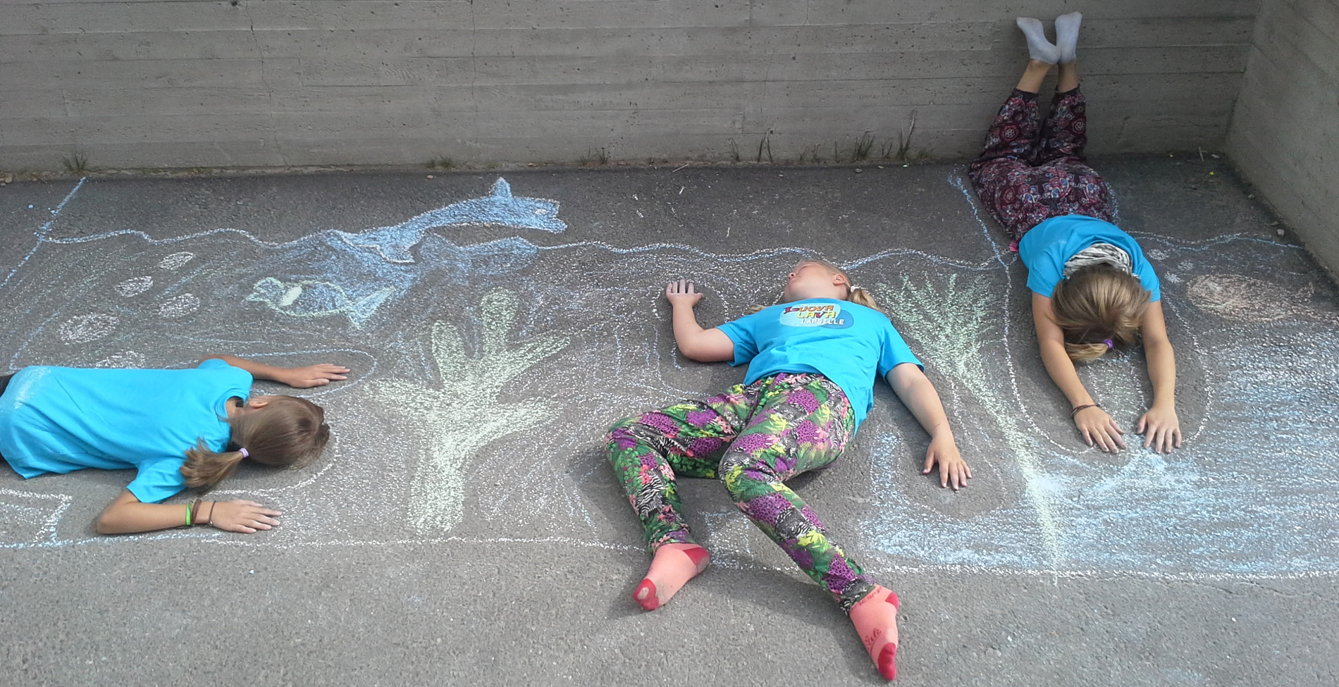 Lapset makaa maassa, missä on piirroksia jotka on tehty väriliiduilla